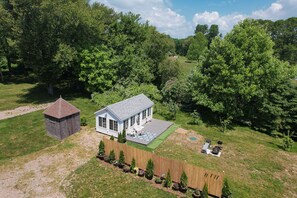Une maison avec une cour clôturée, un petit abri de jardin et un espace patio aménagé avec du mobilier d’extérieur.