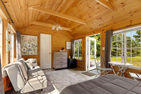 A cozy cabin interior with a sofa, a dining table, and a bed.