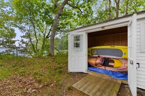 Una pequeña cabaña con terraza de madera y un kayak en su interior.