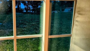 Una habitación con un ventanal grande que da a un área verde con árboles.