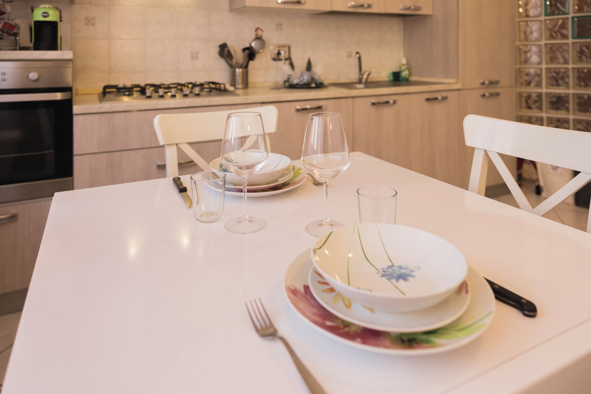 Tavola imbandita con piatti, bicchieri e posate in una cucina moderna.