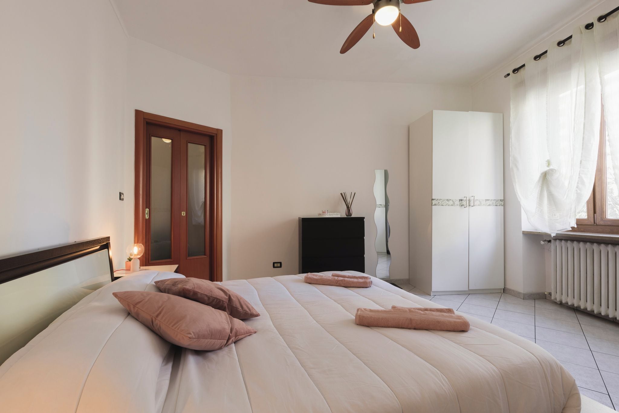 Ein Schlafzimmer mit einem Bett, einem Kleiderschrank, einer Heizung und einem Deckenventilator.