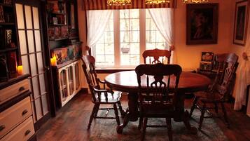 Un comedor con una mesa y sillas de madera, un aparador con puertas de vidrio y una ventana con cortinas.