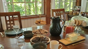 Una mesa de desayuno con varios pasteles, un jarro de jugo y un ablandador de vidrio.
