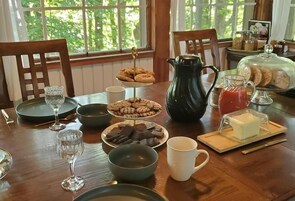Una mesa de desayuno con varios pasteles, un jarro de jugo y un ablandador de vidrio.