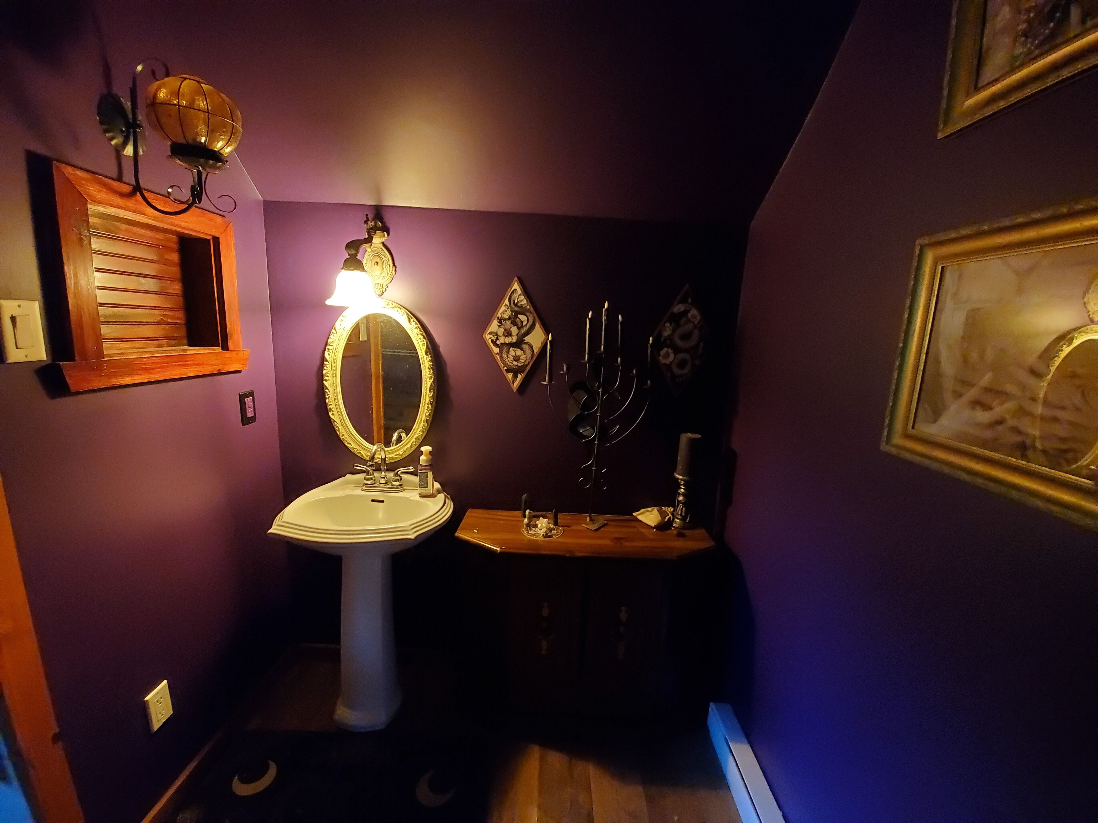 Ein Badezimmer mit einem weißen Waschbecken, einem Spiegel, einer dekorativen Leuchte und einer Menora an der Wand.