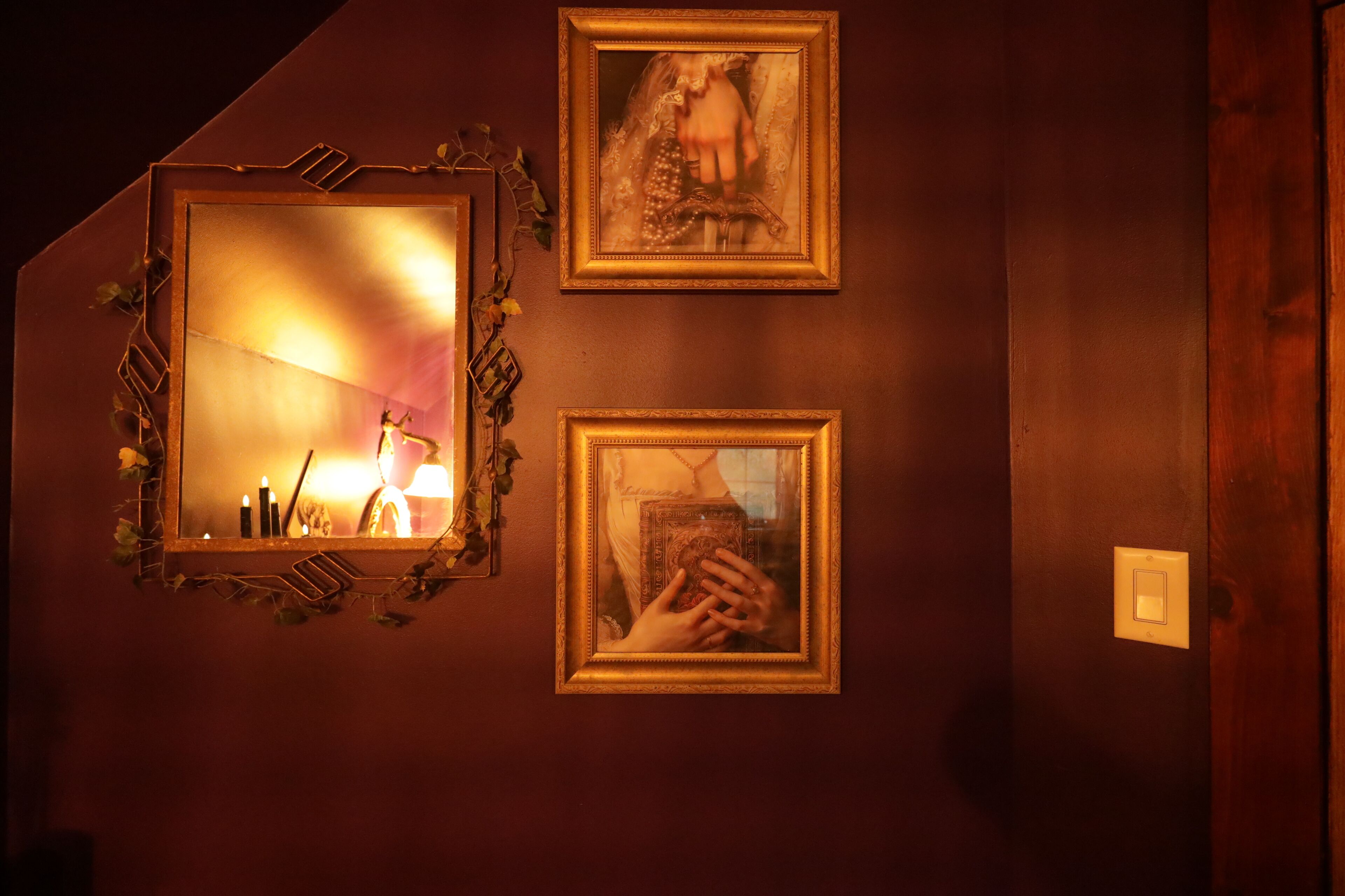 A wall with two framed pictures and a mirror.