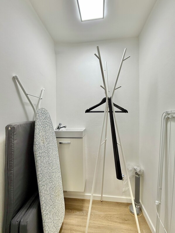 A small, well-lit room with a wooden floor, a white sink, and a drying rack with a black hanger. - 5-7 persons, Wifi, terrace, new, near Nordpark and supermarkets BIELEFELD (Bielefeld)