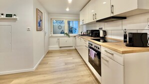 A modern kitchen with white cabinets, a wooden countertop, and a built-in oven. - 5-7 persons, Wifi, terrace, new, near Nordpark and supermarkets BIELEFELD (Bielefeld)
