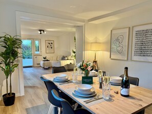 A dining area with a wooden table set for two, a bottle of champagne, and a floral centerpiece. - 5-7 persons, Wifi, terrace, new, near Nordpark and supermarkets BIELEFELD (Bielefeld)