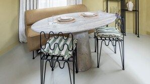 A dining area with a round table, two chairs, a sofa, and a plant on a shelf. - Unique 3 floor tower apartment with AC at Westerpark (Amsterdam)