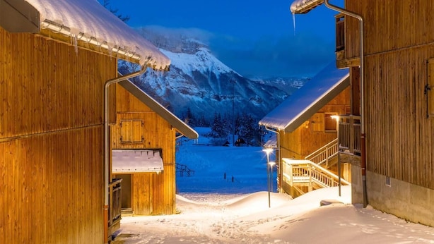 A wooden cabin with a snow-covered roof and a staircase leading to a second level. - Wifi, 200m from resort center, swimming pool, sauna, balcony, parking, tv, ski locker, 31m² (Les Déserts)