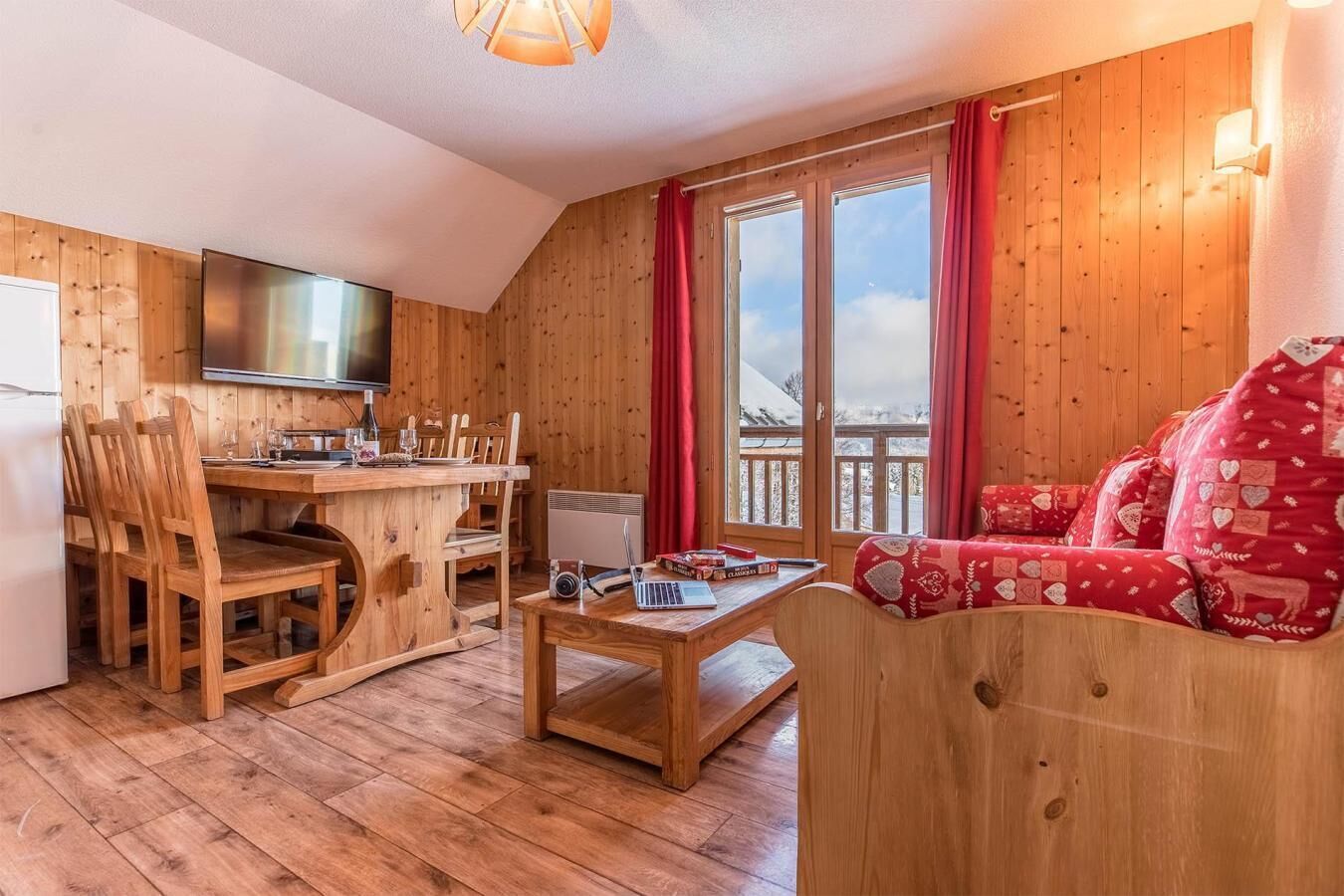 A cozy wooden interior with a dining area, a sofa, and a TV.