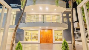 Un edificio moderno de dos pisos con entrada central, puertas de cristal y un balcón.