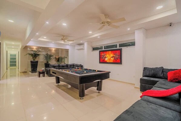 A modern living room with a foosball table, a sofa, and a TV.