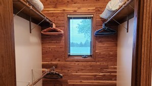 Een smalle kamer met houten paneelwanden, een klein raam en een houten vloer.