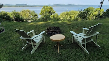 A grassy outdoor area with two Adirondack chairs and a small round table.