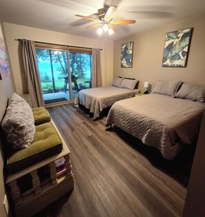 A hotel room with two beds, a green sofa, a ceiling fan, and a view of the outdoors. - Enchanting 3-bedroom house with WiFi in Genoa (Genoa)