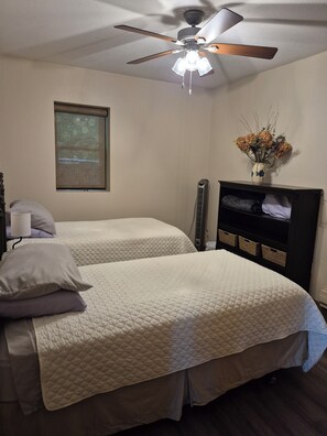 A bedroom with two beds, a ceiling fan, a projector screen, and a dresser with baskets. - Enchanting 3-bedroom house with WiFi in Genoa (Genoa)