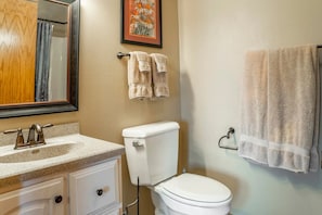 A bathroom with a white sink, a toilet, and two towels hanging on the wall.