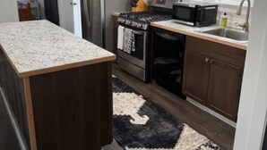 Una cocina moderna con armarios de madera oscura, electrodomésticos de acero inoxidable y encimera de granito.