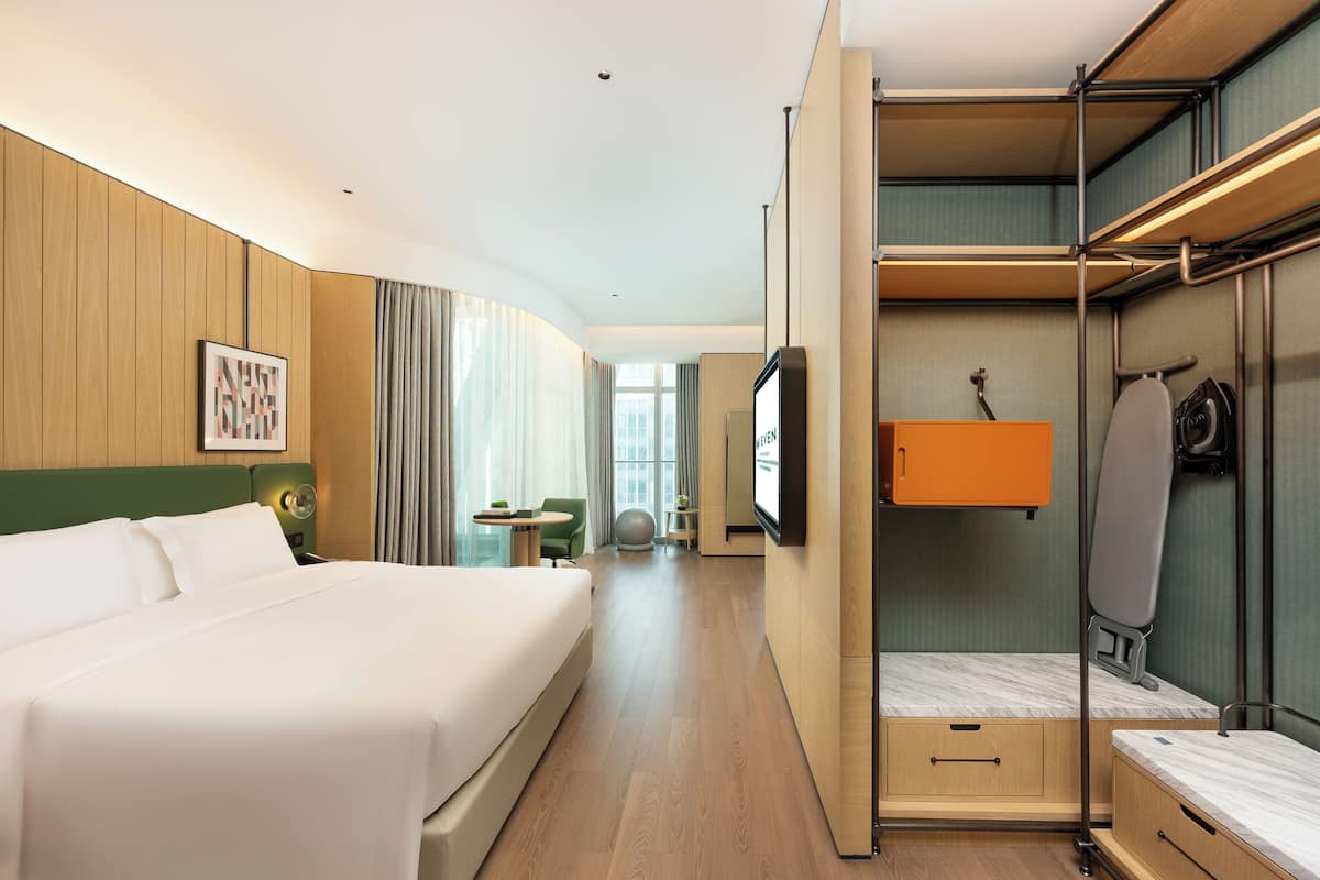 Una habitación de hotel con cama, escritorio, silla, televisor y armario.