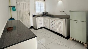 Una cocina con armarios blancos, encimera de mármol y refrigerador.
