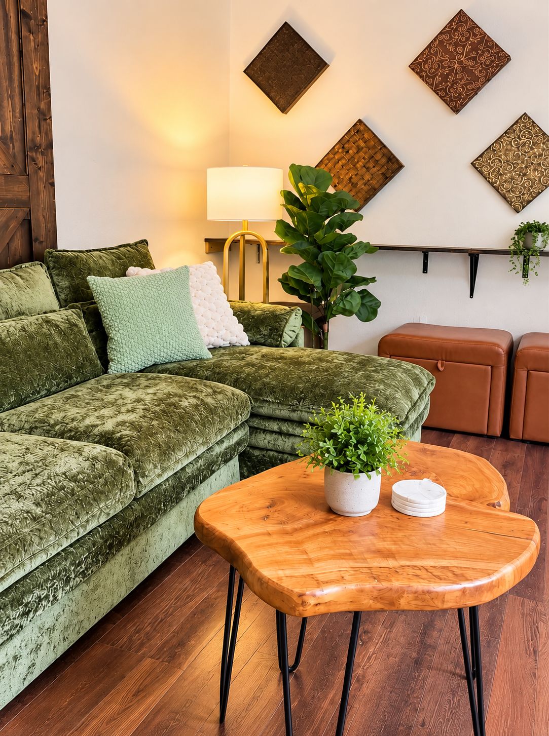 Ein Wohnzimmer mit einem grünen Samtsofa, einem Couchtisch aus Holz mit einer Pflanze und einer Lampe.