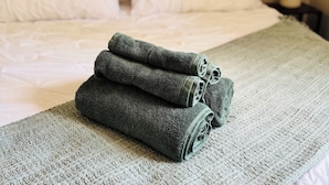 A neatly made bed with white linens and a green textured blanket.