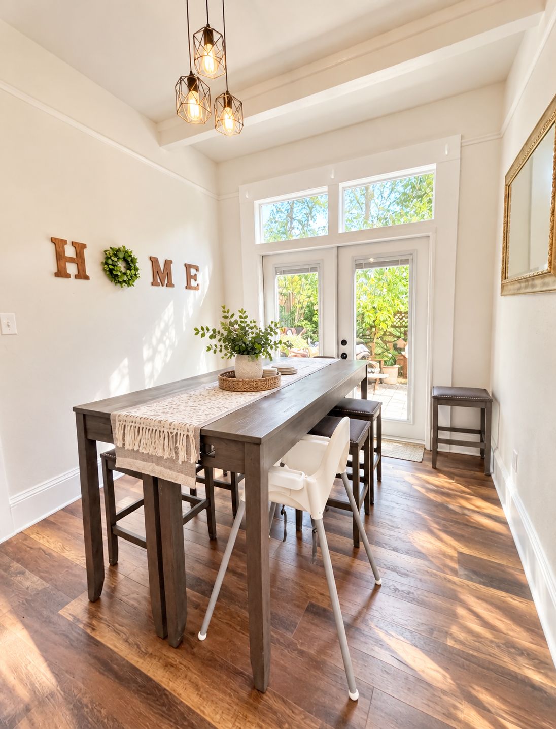 A dining area with a dark wooden table, white chairs, and a hanging light fixture.