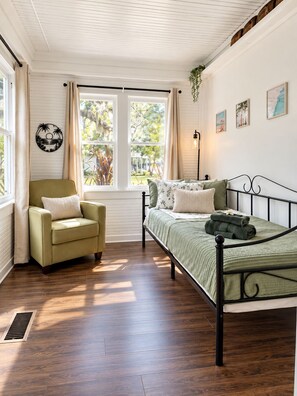 Une chambre à coucher comprenant un lit, une chaise, une fenêtre et un luminaire fixé au mur.