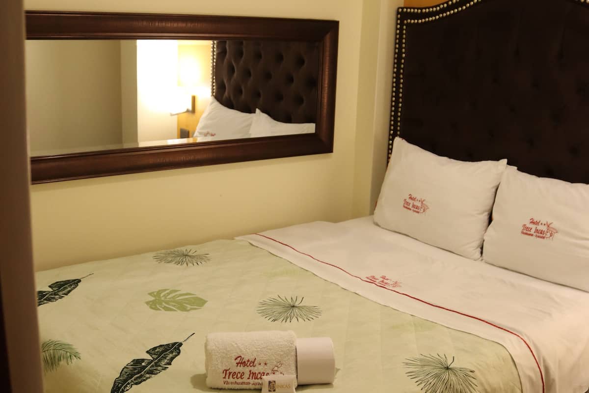 A hotel room with a bed, a mirror, and a pillow with text.