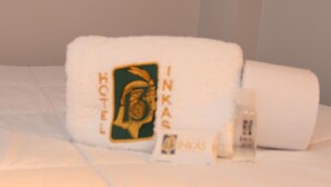 Uma cama de hotel com toalha exibindo o logotipo e nome do hotel.