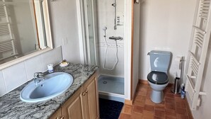 A bathroom with a sink, mirror, shower, toilet, and tiled floor. - Charming gîte - 72 m² - 30 min from the sea (Bellevigny)