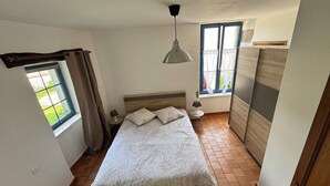 A bedroom with a bed, a hanging light, a window with curtains, and a wardrobe. - Charming gîte - 72 m² - 30 min from the sea (Bellevigny)