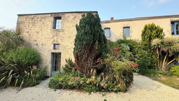 A building with a stone facade, multiple windows, and a gravel driveway. - Charming gîte - 72 m² - 30 min from the sea (Bellevigny)