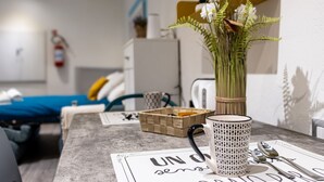 Una moderna camera d'albergo con un letto, un tavolino con un vaso di fiori, un bollitore e una macchina da caffè.