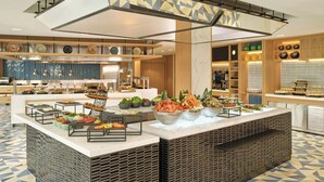 A modern buffet setup with various food stations, a central serving area, and a patterned floor. - Courtyard by Marriott Pyeongtaek (Pyeongtaek)