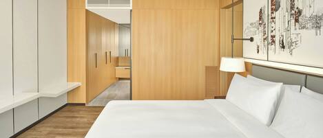 A modern hotel room with a large bed, wooden wardrobe, and a cityscape artwork on the wall.