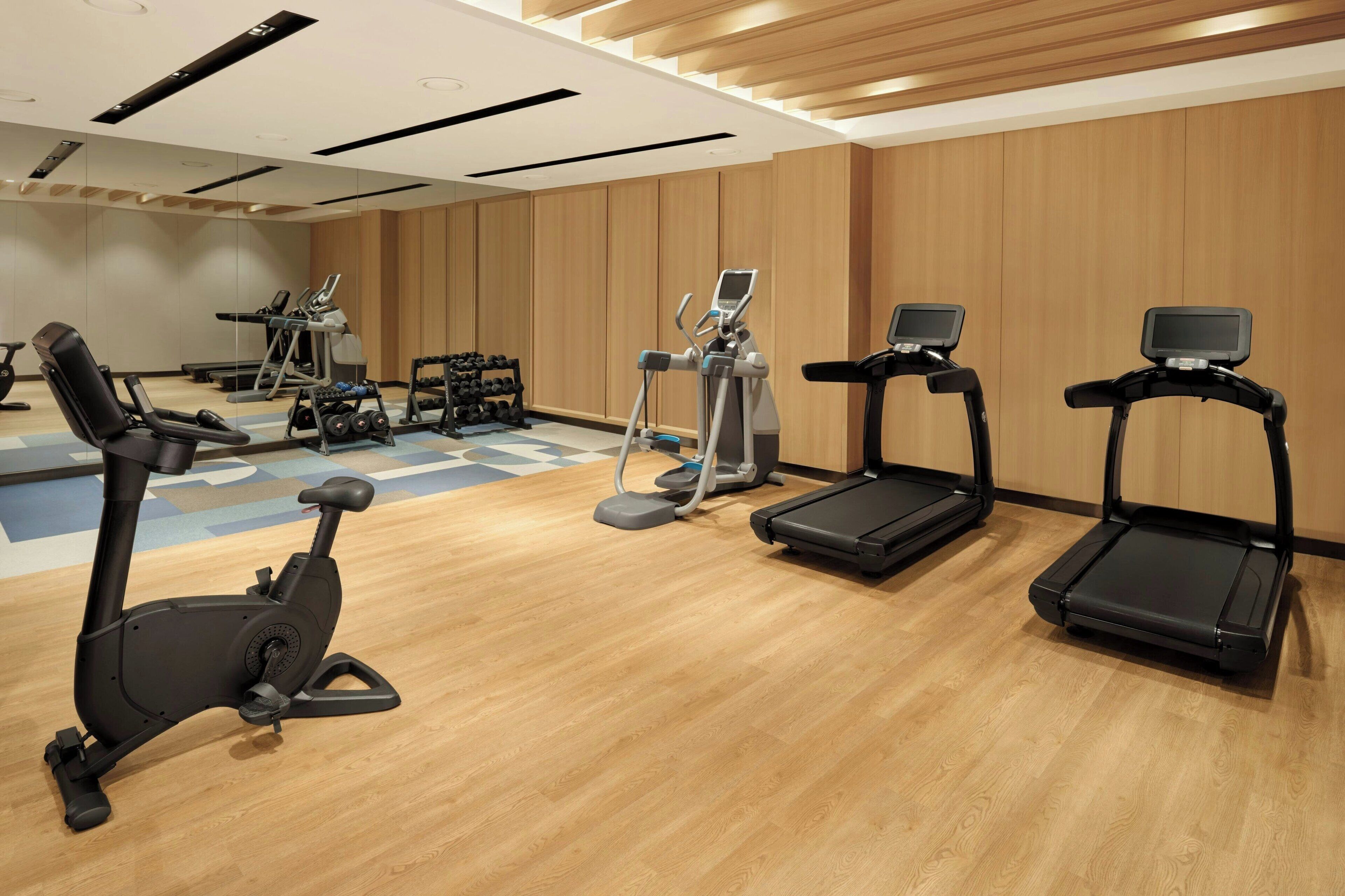 A gym with exercise equipment including treadmills, an elliptical, and dumbbells.