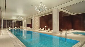 Ein großer, überdachter Pool mit Liegestühlen und einer Kristallleuchter.