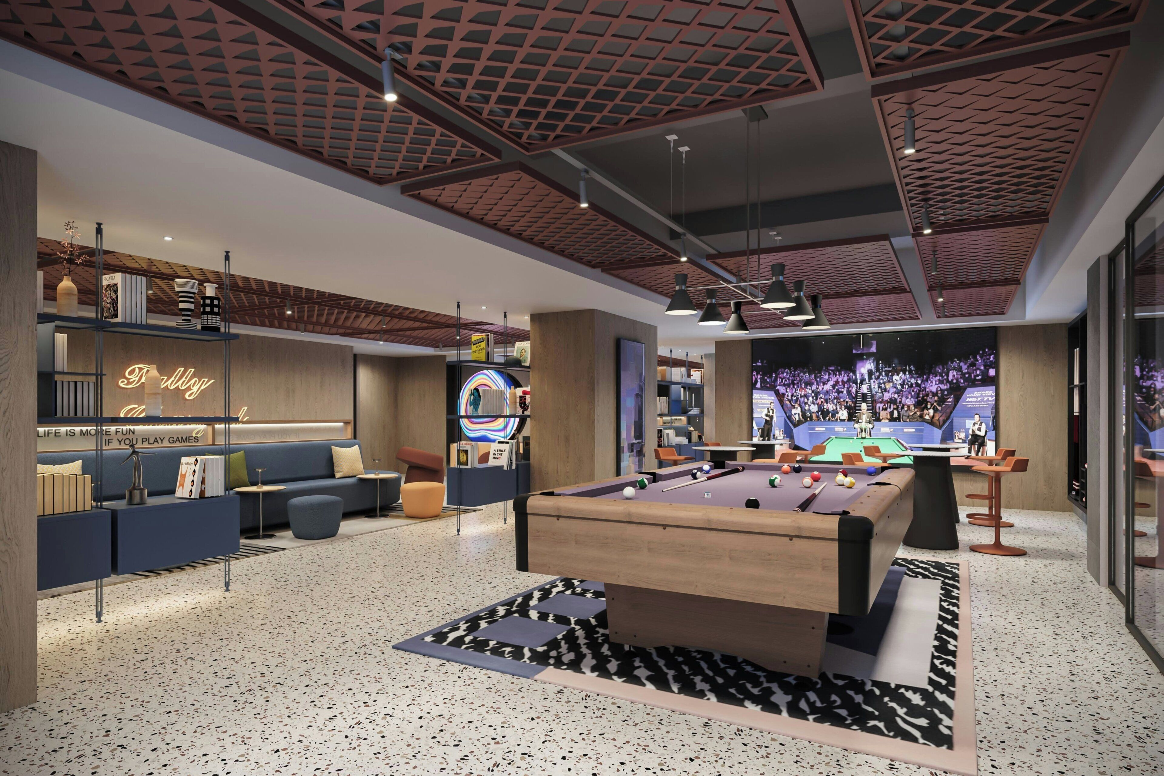 A modern indoor pool area with a pool table, lounge seating, and a large screen displaying a sports event.