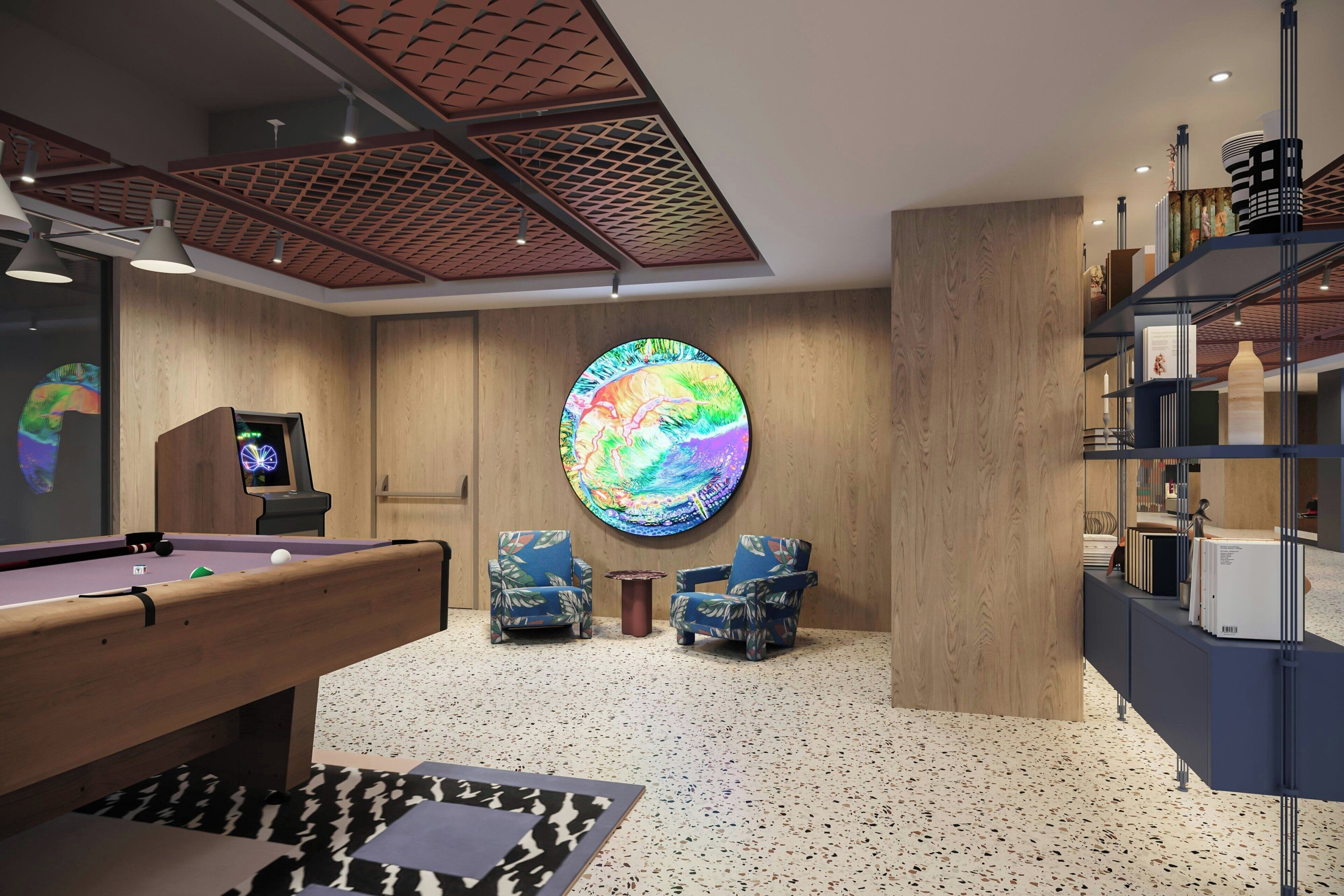 A modern lounge area with a pool table, two armchairs, a colorful globe artwork, and a bookshelf.