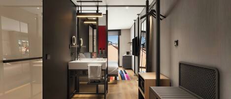 A modern hotel room with a wooden floor, a bed with a headboard, a small desk, a chair, a mirror, and a window.