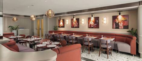 A restaurant interior with round tables, red seating, and artwork on the walls.