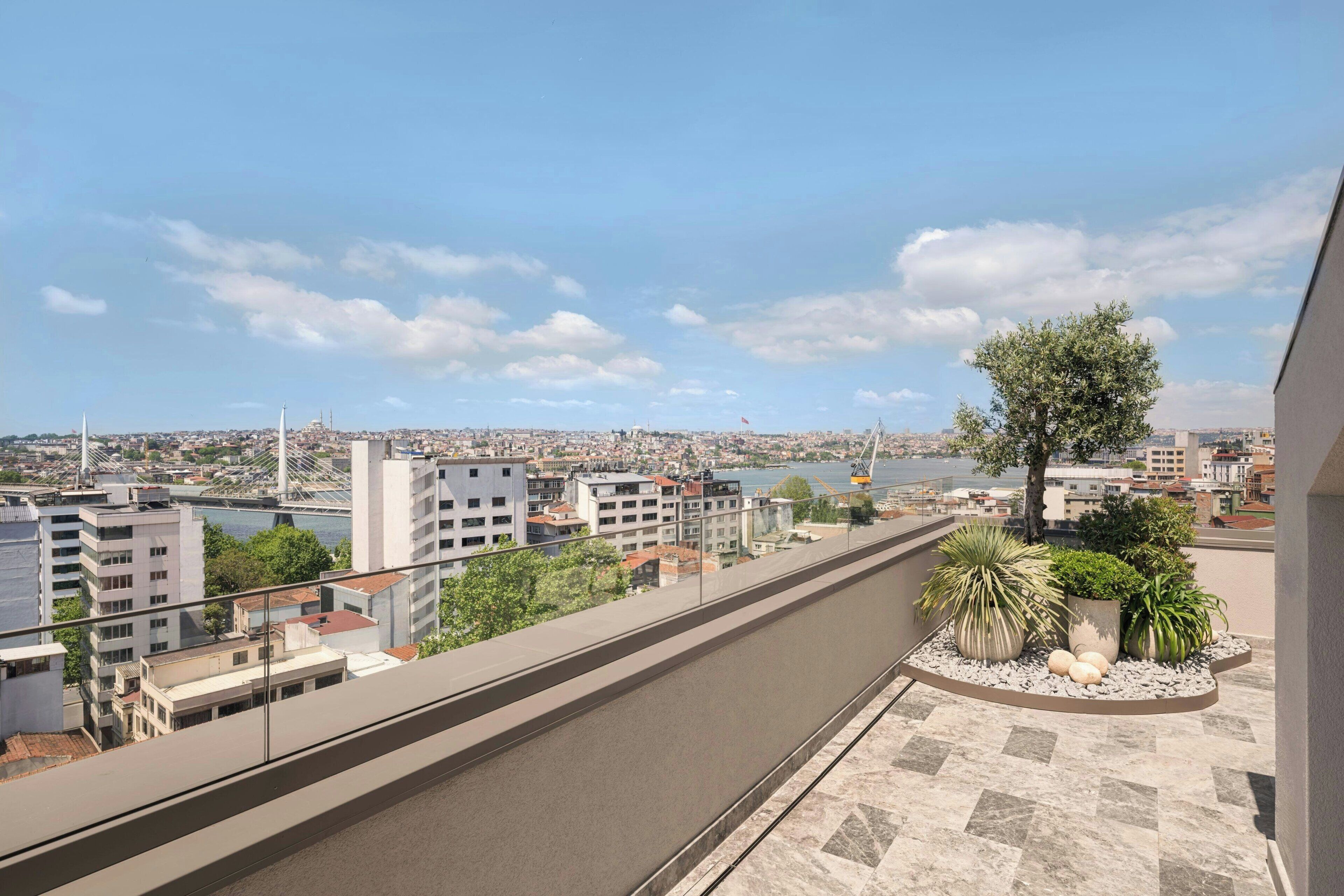 A balcony with a view of a cityscape, including a river and a bridge.