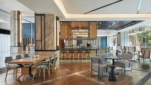 A spacious hotel lobby with a central bar area, seating arrangements, and a modern kitchen in the background. - Four Points By Sheraton Xishuangbanna (Xishuangbanna Dai)