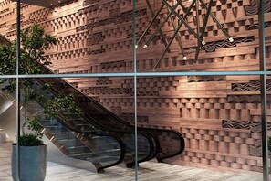 A modern building facade with a brick pattern and an escalator.