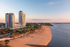 A coastal hotel with a beach view, two high-rise buildings, and a promenade.