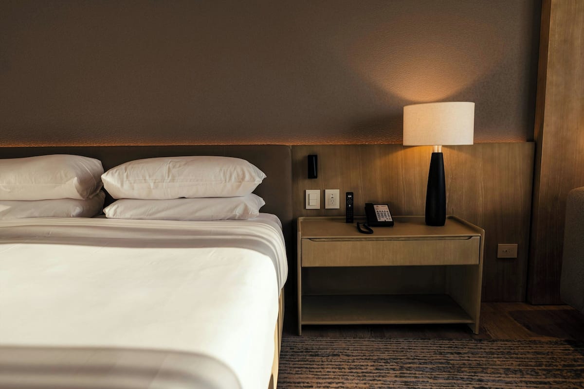 Ein Hotelzimmer mit Bett, Nachttisch, Lampe und Telefon.